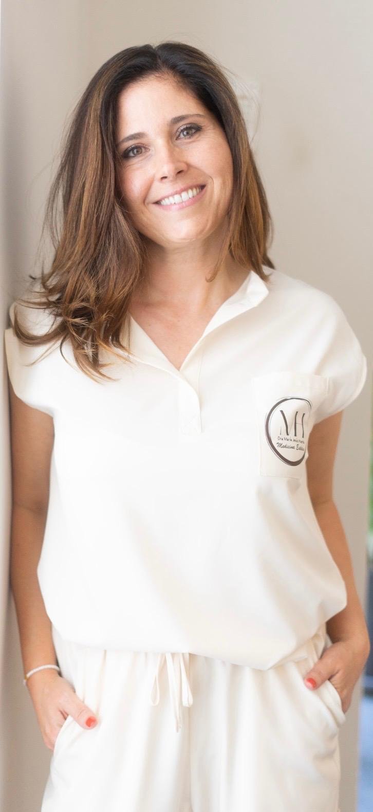 La Dra. María Jesús Huertas con uniforme claro de consulta, sonriendo