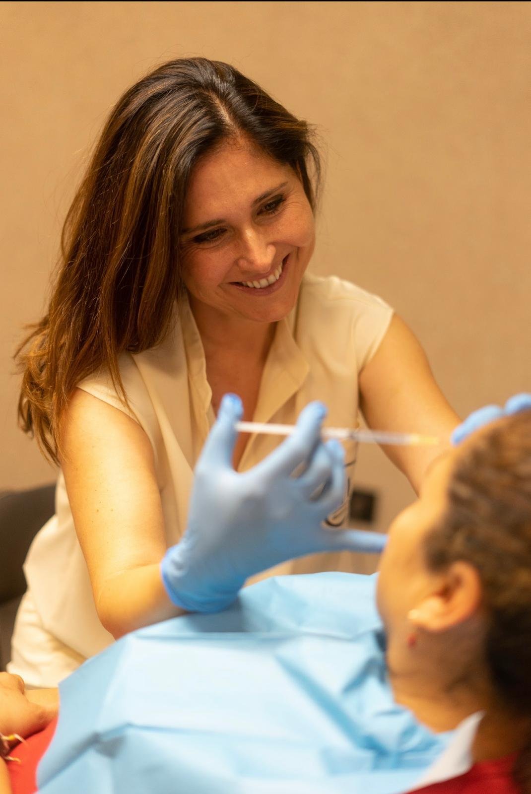 La Dra. Huertas, con guantes, aplicando un tratamiento de medicina estética facial a una paciente